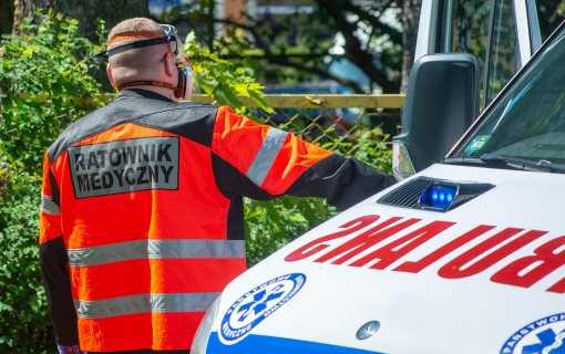 ratownik medyczny odwrócony tyłem i karetka pogotowia